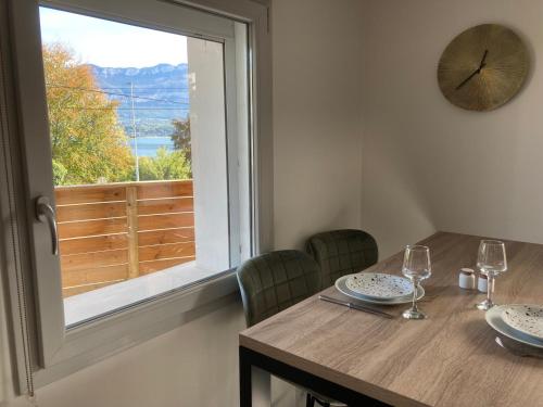 une table avec des verres, une horloge et une fenêtre dans l'établissement Les Mirandelles - vue/accès lac, au Bourget-du-Lac