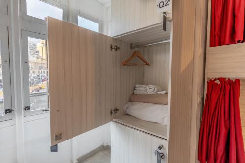 ein kleines Zimmer mit einem Bett und einem roten Vorhang in der Unterkunft The Rose Hostel in St Julian's