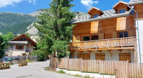 a wooden house with a fence in front of it at Magnifique duplex au pied des pistes, rénové dans maison de pays in Le Monêtier-les-Bains