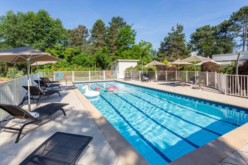 einen Pool mit Stühlen und Sonnenschirmen in der Unterkunft Sweet Home by Novotel Bordeaux Mérignac in Mérignac