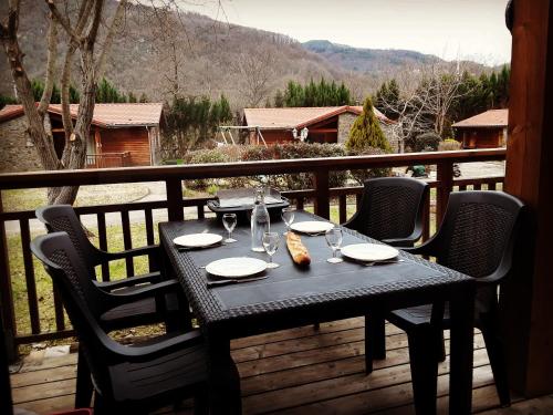 a table with glasses and food on a balcony at Chalets à 10 minutes de Foix in Mercus-Garrabet