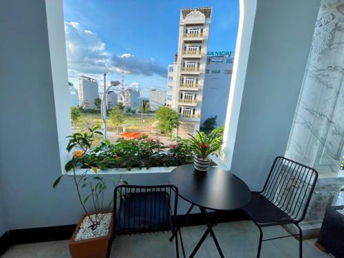 een tafel en stoelen op een balkon met een raam bij Queen Sea Hotel in Phan Thiet