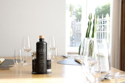 a bottle of wine sitting on a table with glasses at Villa les érables Restaurant Linea in Spa
