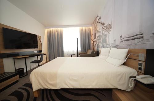 um quarto de hotel com uma cama grande e uma televisão em Novotel Vilnius Centre em Vilnius