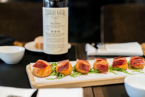 a plate of food on a table with a bottle of wine at Áurea Washington Irving by Eurostars Hotel Company in Granada