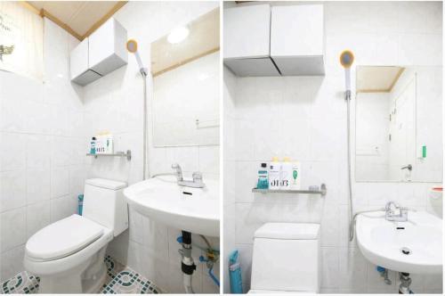 a white bathroom with a toilet and a sink at Ria House in Goyang