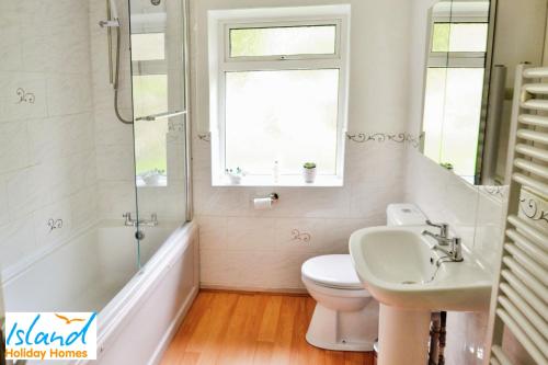 ein Bad mit einem Waschbecken, einem WC und einem Fenster in der Unterkunft Baltija in Ventnor
