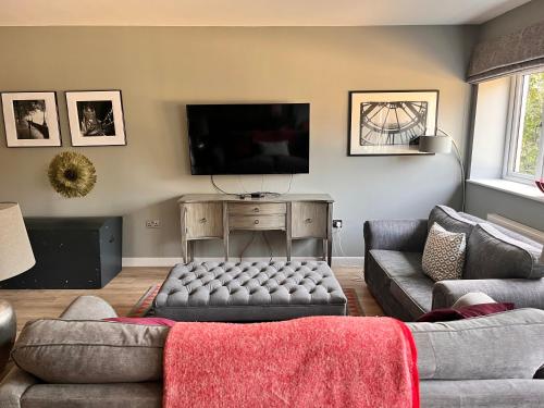 ein Wohnzimmer mit einem Sofa und einem Flachbild-TV in der Unterkunft The Coach House in Warnham