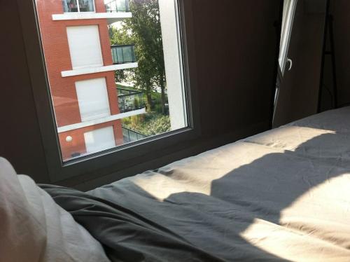 een slaapkamer met een bed en een raam met uitzicht bij 4 pièces au Stade de France 80 m2 in Saint-Denis