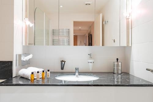 une salle de bain avec un lavabo et un miroir dans l'établissement Veeve - Eiffel Skies, à Paris