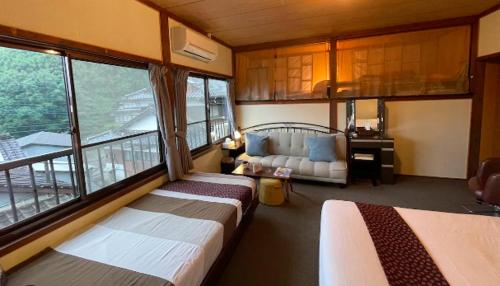 um quarto com duas camas e um sofá num quarto em Private & Cozy Lodge - basecamp Imari em Imari