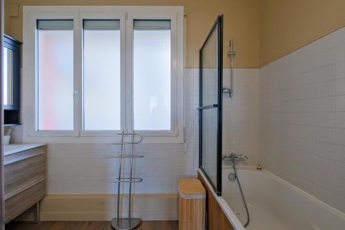 een badkamer met een douche en een bad en een raam bij Paquebot - Appt vue mer in Saint-Nazaire