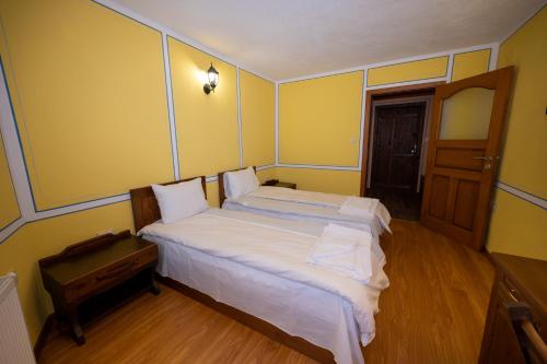 a bedroom with two beds in a room with yellow walls at Недкова къща in Koprivshtitsa