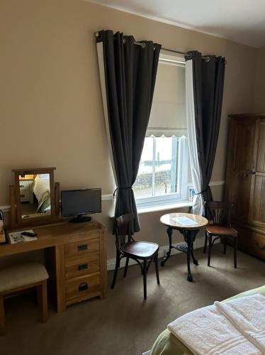 a bedroom with a desk and a bed and a window at Admiral MacBride in Plymouth