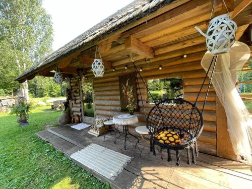 a log cabin with a table and a grill at Viesu Nams “Noras” in Ķesterciems