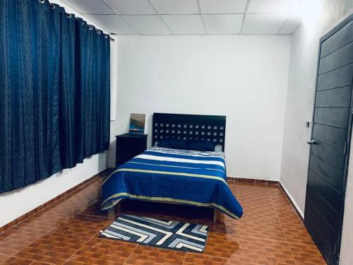 um quarto com uma cama com um cobertor azul em Departamento en el centro, 2 recamaras, estacionam em Paraíso