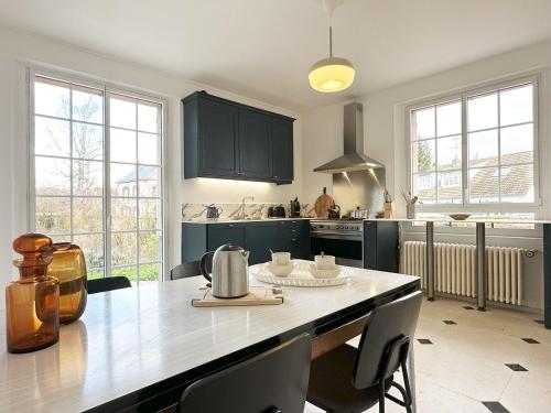 una cocina con armarios negros y una mesa con sillas en La Meslaysienne - Comfortable house, swimming pool, en Meslay-le-Vidame