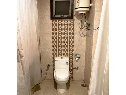 a bathroom with a toilet and a tv on the wall at The Silverwood, Gangtok in Gangtok