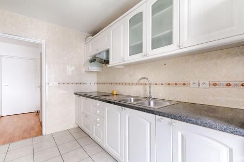 una cocina con armarios blancos y fregadero en Saint Denis/Leon Nozal : Magnifique Apartment 5P en Saint-Denis