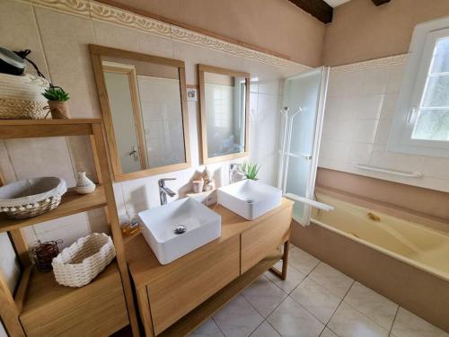 une salle de bain avec deux lavabos, une baignoire et un miroir dans l'établissement La Cabane Wave House - Maison cosy au calme proche lac, à Sainte-Eulalie-en-Born