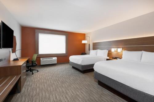 コロラドスプリングスにあるHoliday Inn Express & Suites - Colorado Springs South I-25, an IHG Hotelのベッド2台、薄型テレビが備わるホテルルームです。