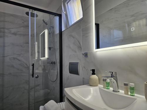 a white bathroom with a shower and a sink at Apartments Vjera Rukavac in Rukavac