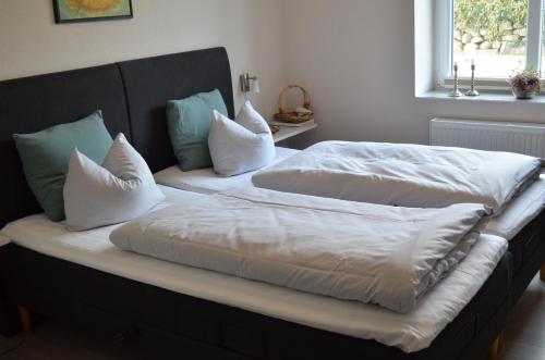 two beds with white sheets and pillows in a bedroom at Naturperlen in Rødekro