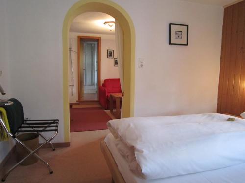 a bedroom with a bed and a hallway with a chair at Gästehaus Unruh in Oberammergau