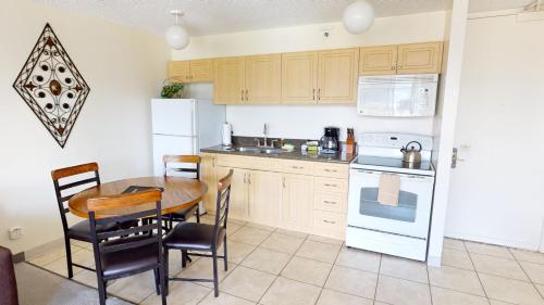 een keuken met een tafel en stoelen en een witte koelkast bij One-Bedroom Apartment in Honolulu