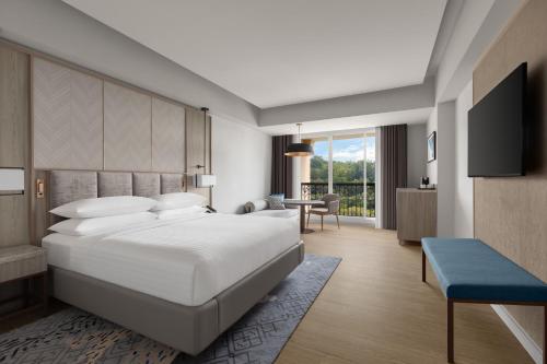 Schlafzimmer mit einem großen weißen Bett und einem Schreibtisch in der Unterkunft Putrajaya Marriott Hotel in Putrajaya