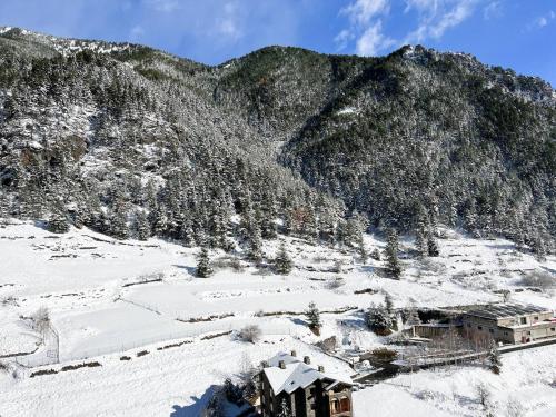 a snow covered mountain with a building in the foreground at Vistas PRECIOSAS Al Valle De Arinsal - 6PAX- A Pie De Pistas & ESQUÍ - Free Parking l by BonesVacances in Arinsal
