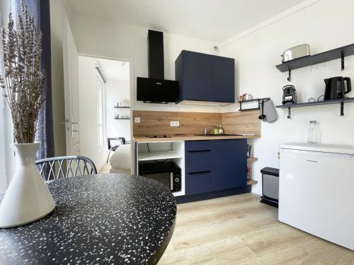 Una cocina con una mesa negra y un refrigerador. en Le Lumineux - Cœur de Ville, en Chartres