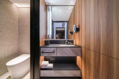 uma casa de banho com um lavatório, um WC e um espelho. em Intercity Hangzhou West Lake Huanglong Hotel em Hangzhou