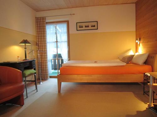 a bedroom with an orange bed and a window at Gästehaus Unruh in Oberammergau