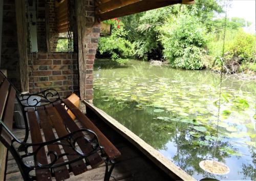 a bench sitting on a porch looking at a pond at Le Lavoir Secret - hébergement atypique dans un joli cadre bucolique in Dangeau