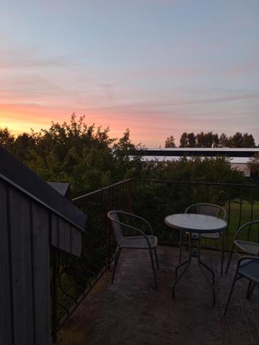 a table and chairs on a balcony with a sunset at Jūras sāga in Pāvilosta