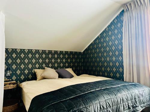 - une chambre avec un lit et du papier peint vert dans l'établissement Kaffestugan, à Hällefors