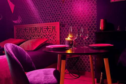 une chambre violette avec une table et deux verres de vin dans l'établissement Love Room L' Orientale / Jacuzzi / Sauna, à Château-Landon
