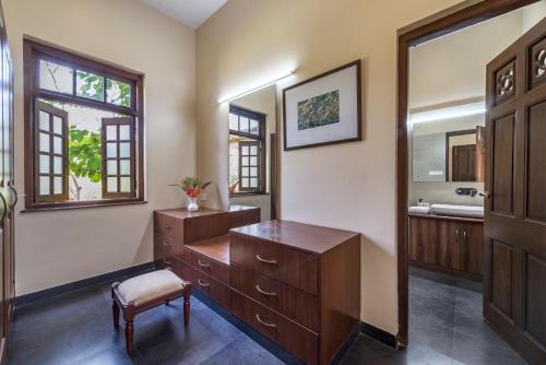 a bathroom with a wooden dresser and a mirror at SaffronStays Mograa laffaire in Alibaug
