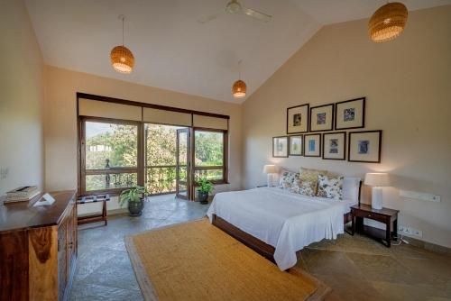 a bedroom with a bed and a large window at SaffronStays Mograa laffaire in Alibaug