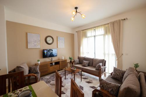 a living room with a couch and a clock on the wall at 1 Bedroom Lake Victoria View Apartment in Entebbe