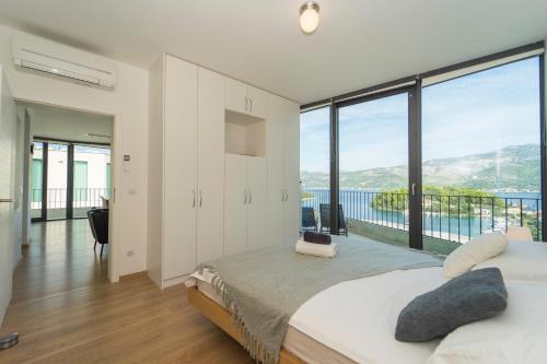 a bedroom with a large bed and large windows at White Cloud Apartments in Korčula