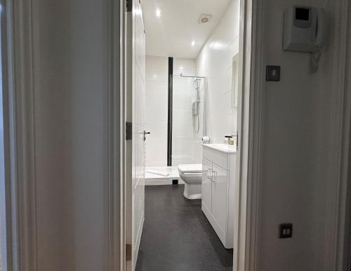 a white bathroom with a toilet and a sink at Apt 1, Soho Apartments 1st floor by Indigo Flats in London