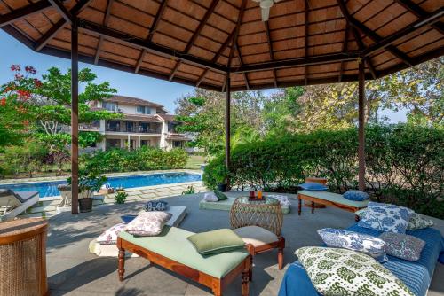 an outdoor patio with couches and a pool at SaffronStays Mograa L'Affaire - 5BR pet-friendly villa with private pool, gazebo & lawns near Kankeshwar Temple in Alibaug