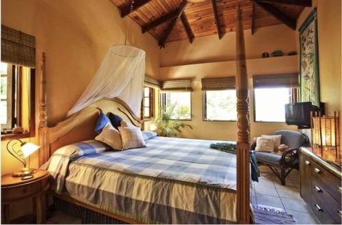 ein Schlafzimmer mit einem Himmelbett und einem TV in der Unterkunft Amazing 9 BR Villa in Cap Estate in Cap Estate
