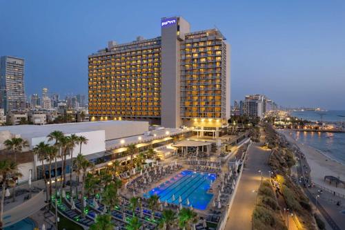 a large building with a pool in front of a city at The Vista At Hilton Tel Aviv in Tel Aviv