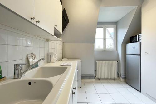 eine weiße Küche mit einer Spüle und einem Kühlschrank in der Unterkunft Le Spacieux in Chartres