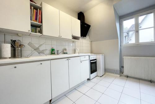 une cuisine blanche avec des armoires blanches et une fenêtre dans l'établissement Le Spacieux, à Chartres