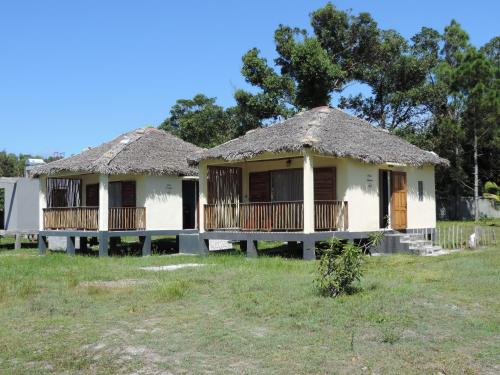 Dos casas con techo de paja en un campo en LE SERENITY LODGE, en Mahanoro