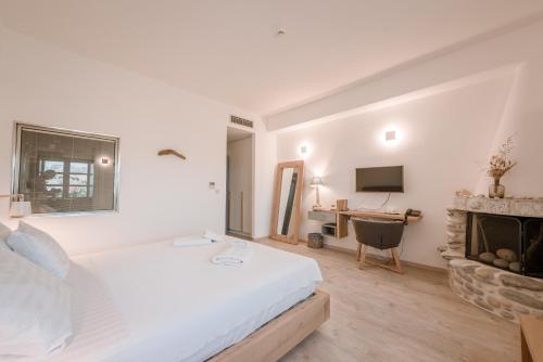 a white bedroom with a bed and a fireplace at Alika Resort in Álika
